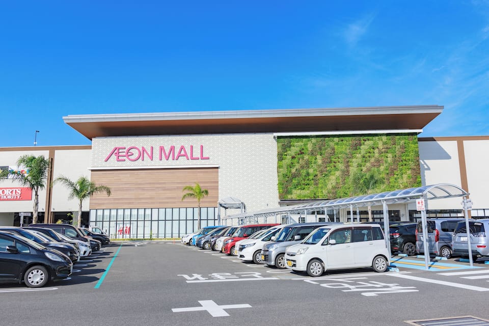 Un pàrquing amb cotxes davant d'un centre comercial.