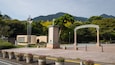 A park entrance with a clock, a stone archway, and a mountain in the background.