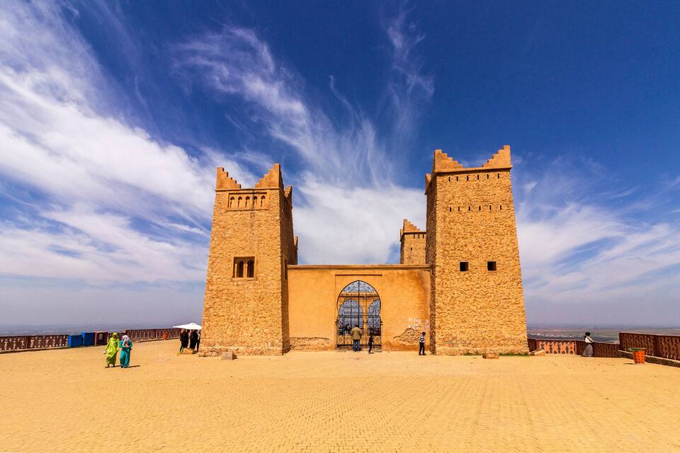 A historic stone fortress with two towers and a large arched entrance.