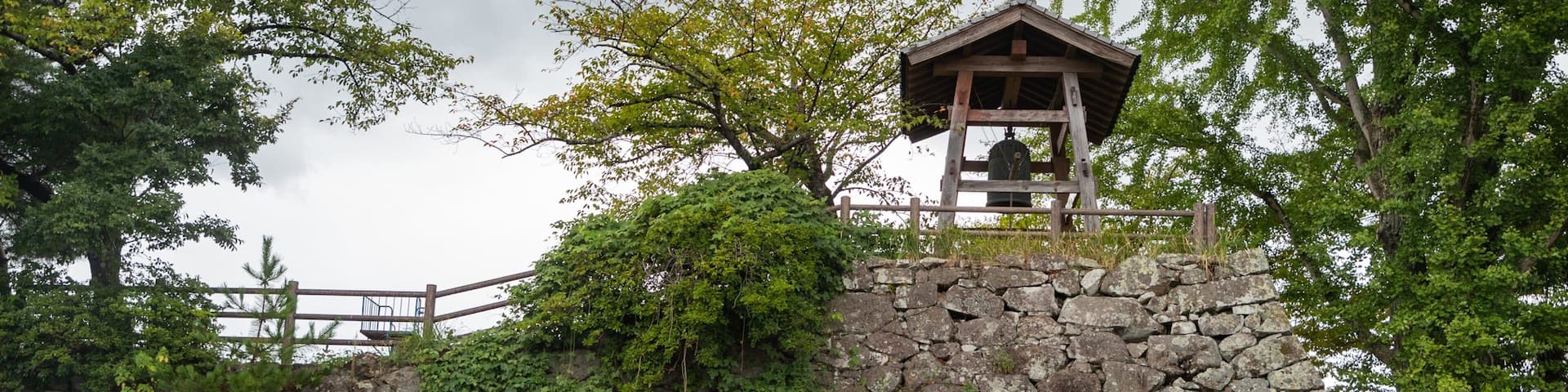 Un muro de piedra con una torre de madera en la parte superior.