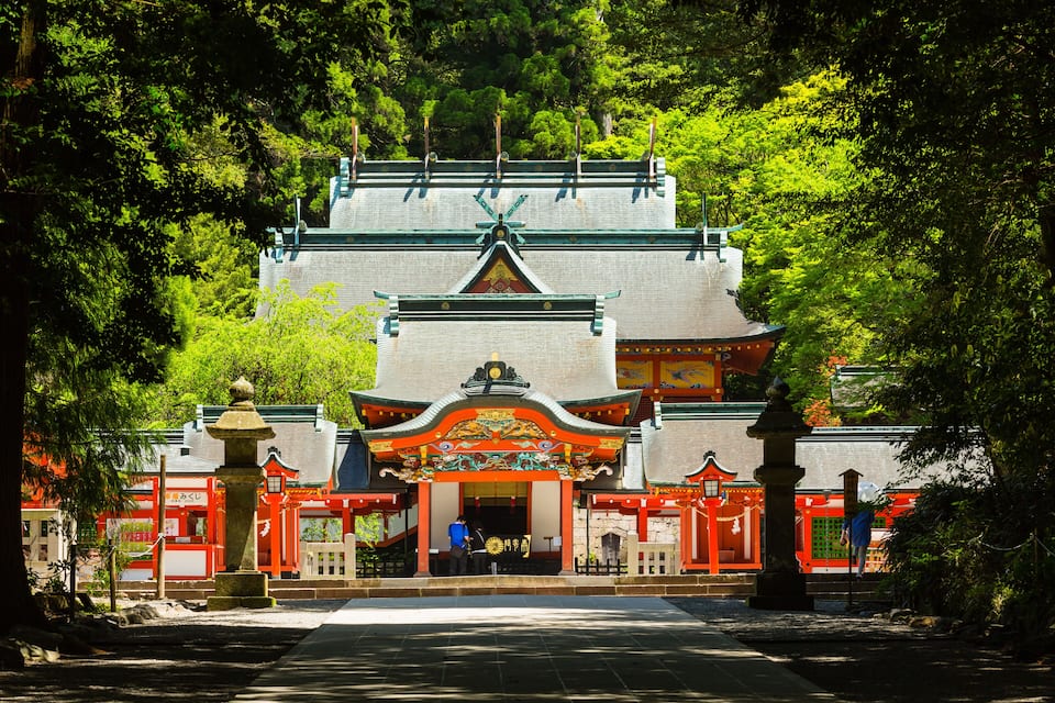 A traditional Japanese temple with a red torii gate, surrounded by lush greenery.