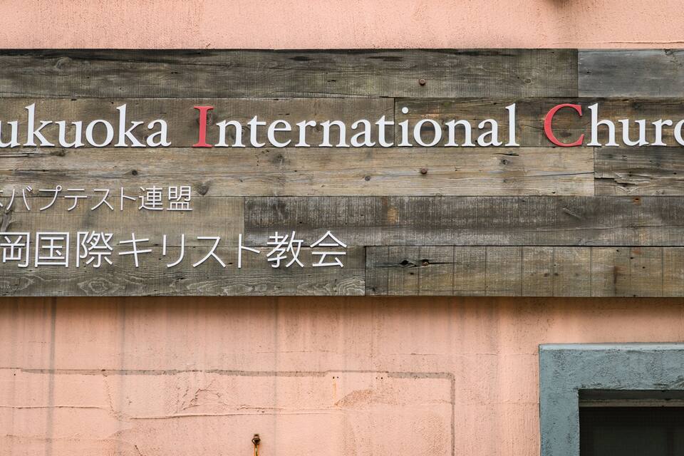 A wooden sign with the text "Fukuoka International Church" and Japanese characters.