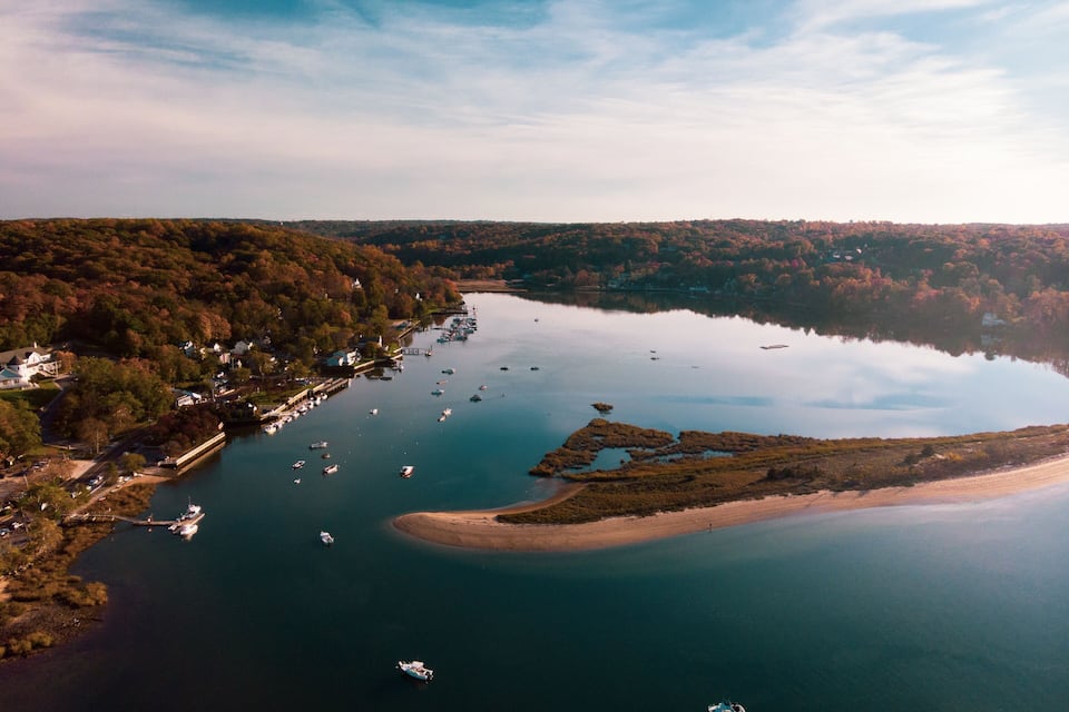 A lake surrounded by forested hills with boats anchored near the shore.