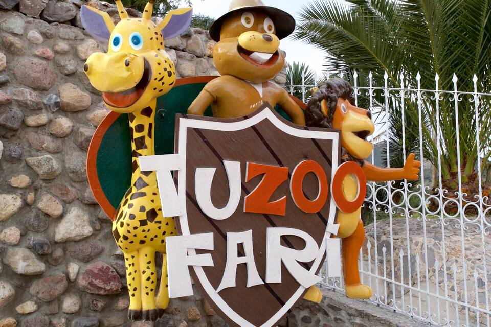 Señal para el Zoológico Tuzo con una jirafa y un león como mascota.