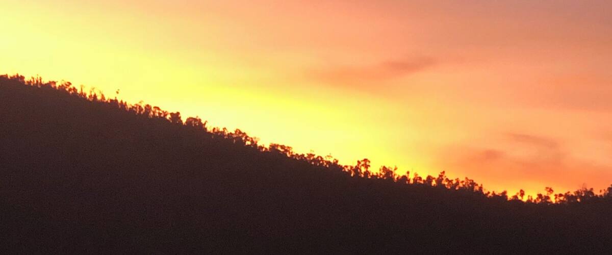 A sunset over a lake with silhouettes of people on kayaks.