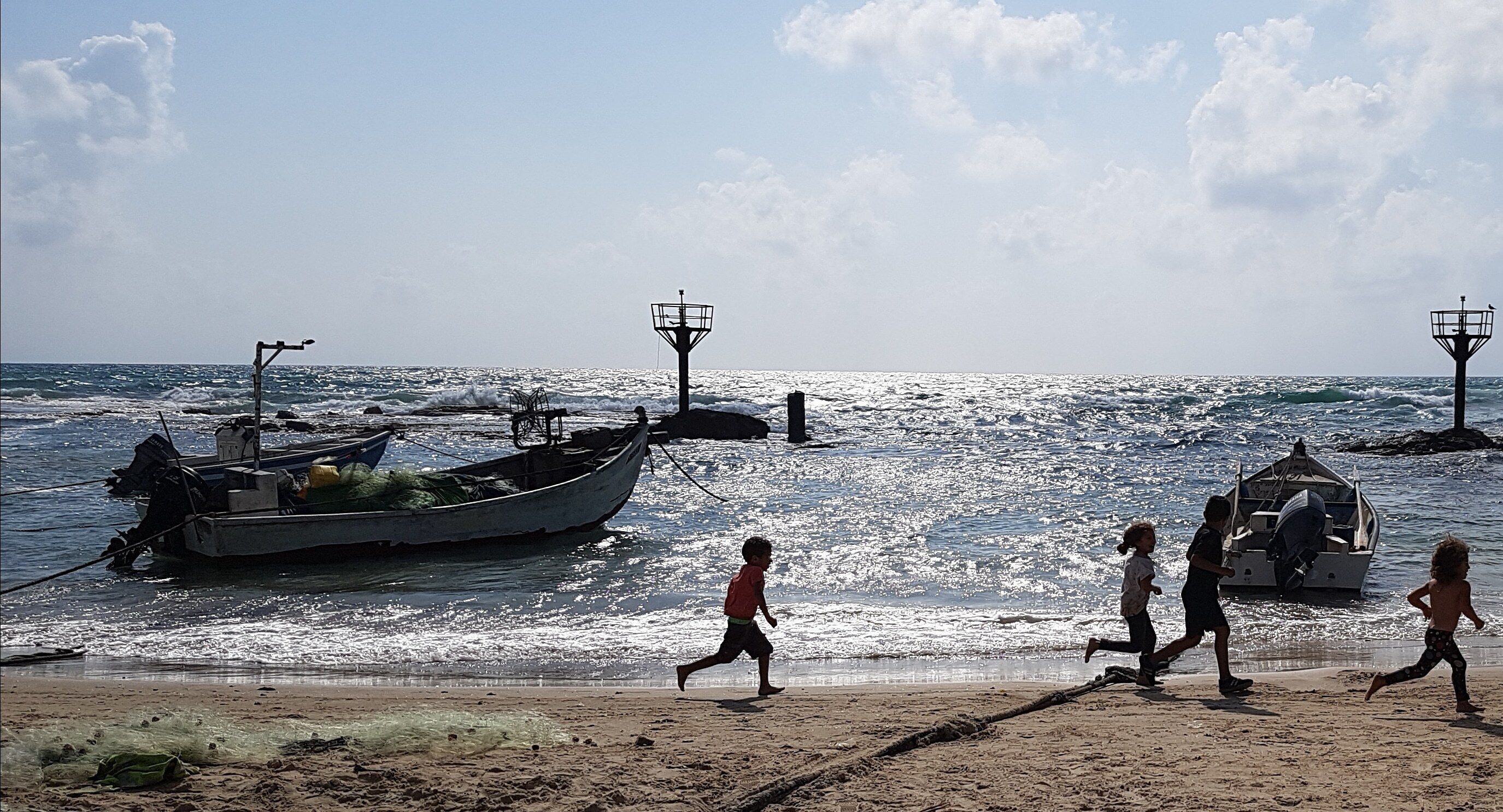 A beach with boats and a lighthouse.