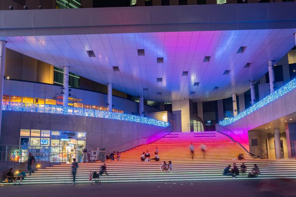 Un edifici modern amb una escala ben il·luminada i trams deutes.