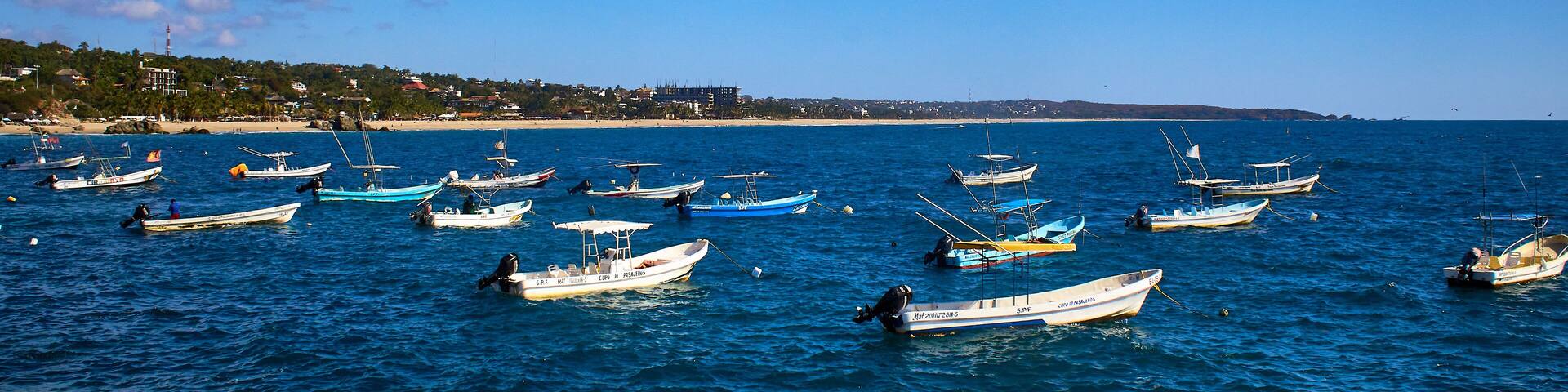 a lot of ships on the sea with blue sky , puerto escondido oaxaca