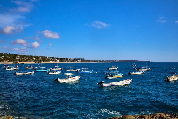 a lot of ships on the sea with blue sky , puerto escondido oaxaca