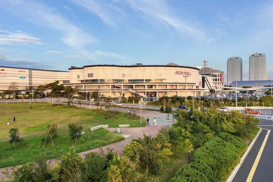 A large commercial building with a parking lot and a grassy area in front.