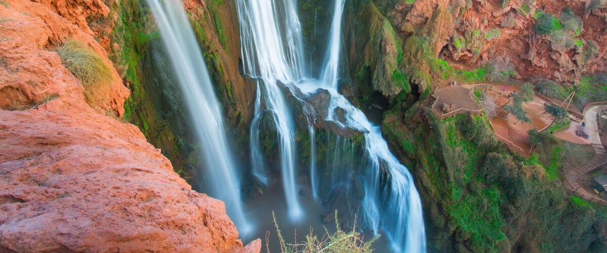 A multi-tiered waterfall surrounded by rocky terrain and greenery.