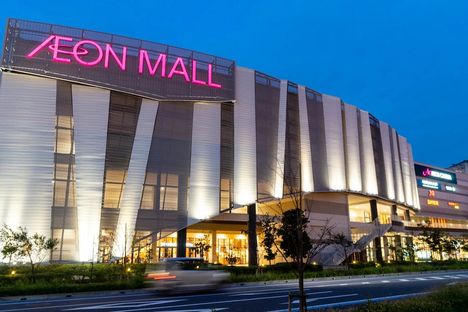 Um shopping moderno com um letreiro de néon chamativo que diz "AEON MALL".