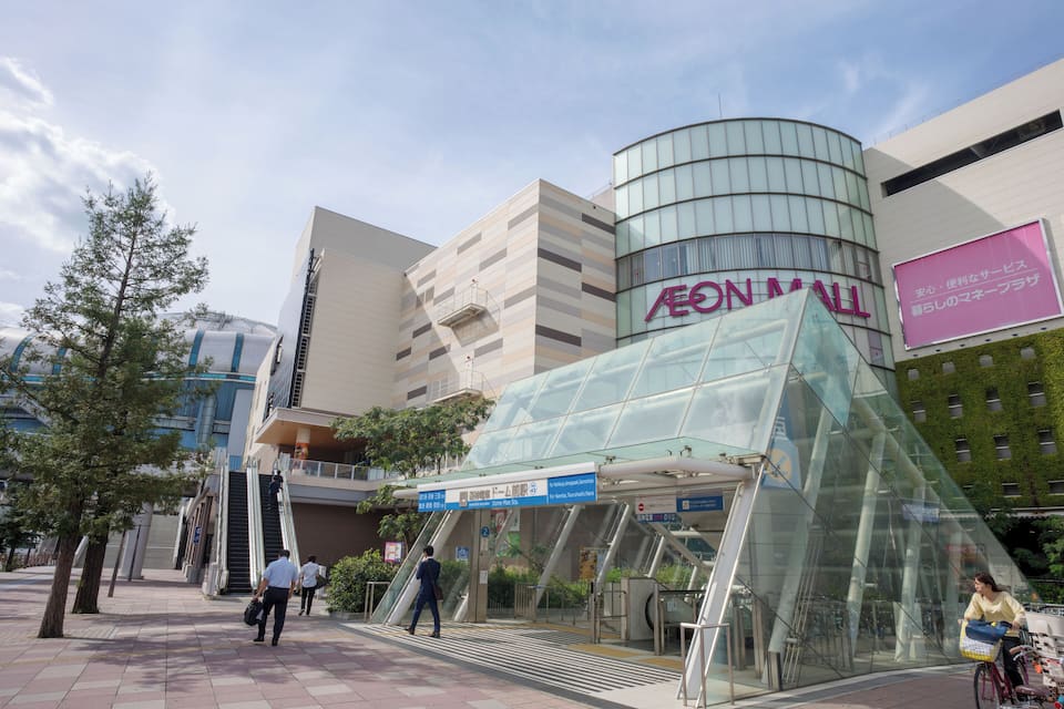 Un centre commercial moderne avec une entrée en verre et une enseigne indiquant « AEON MALL ».