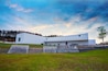 A modern white building with a sloped roof and a grassy area in front.