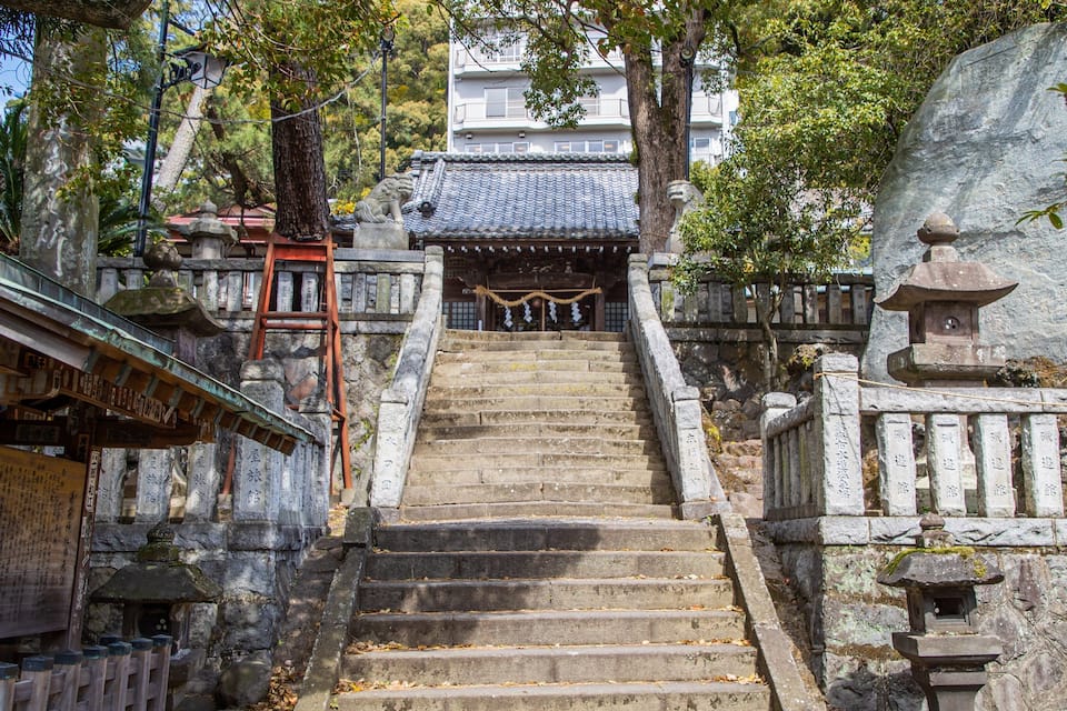 A stone staircase leading to a traditional Japanese building with a tiled roof.