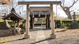 Ein traditionelles japanisches Torii-Tor mit einer Holzhütte links und einem Steinlaternen rechts.