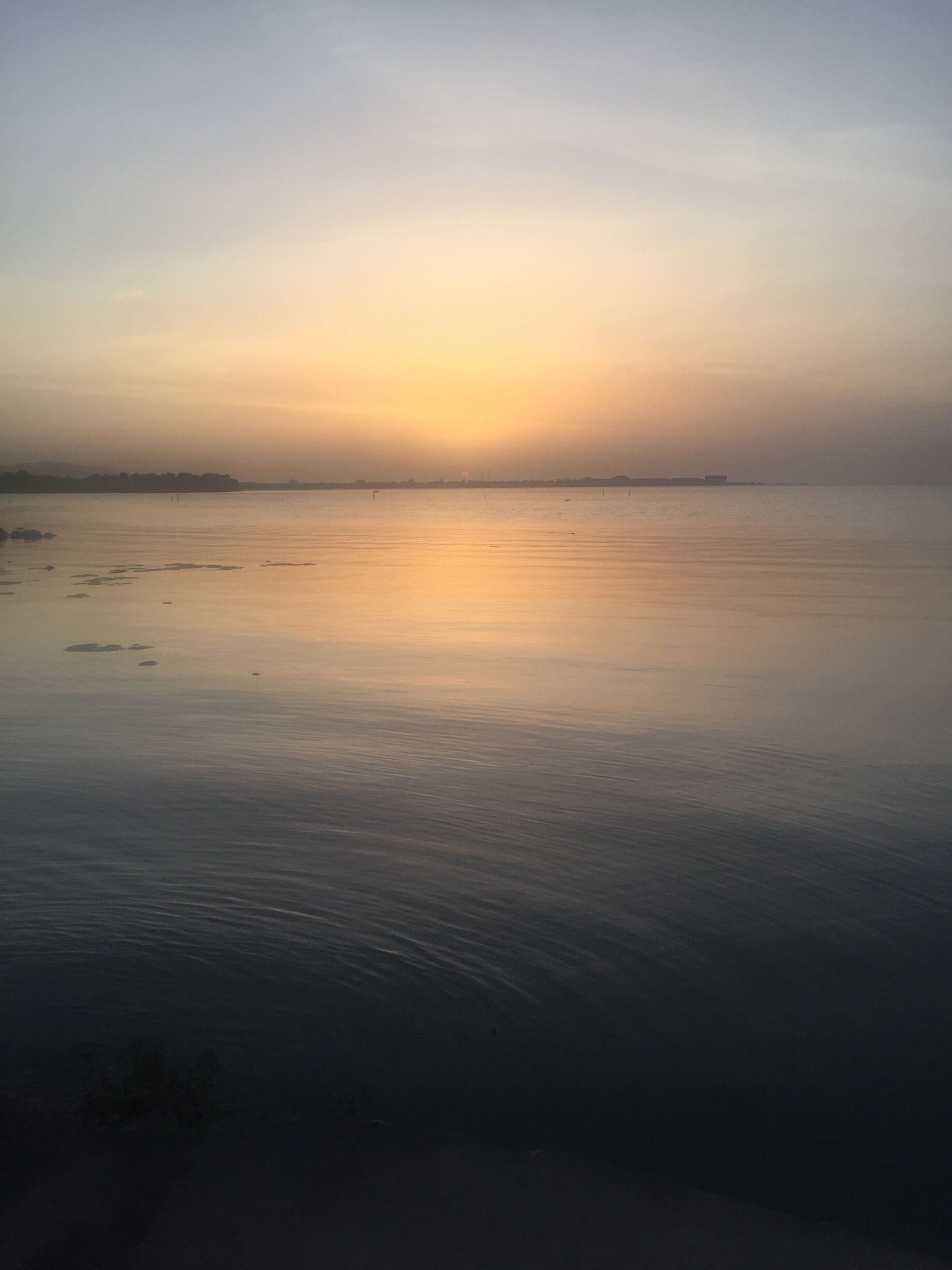 Água calma refletindo um pôr do sol.