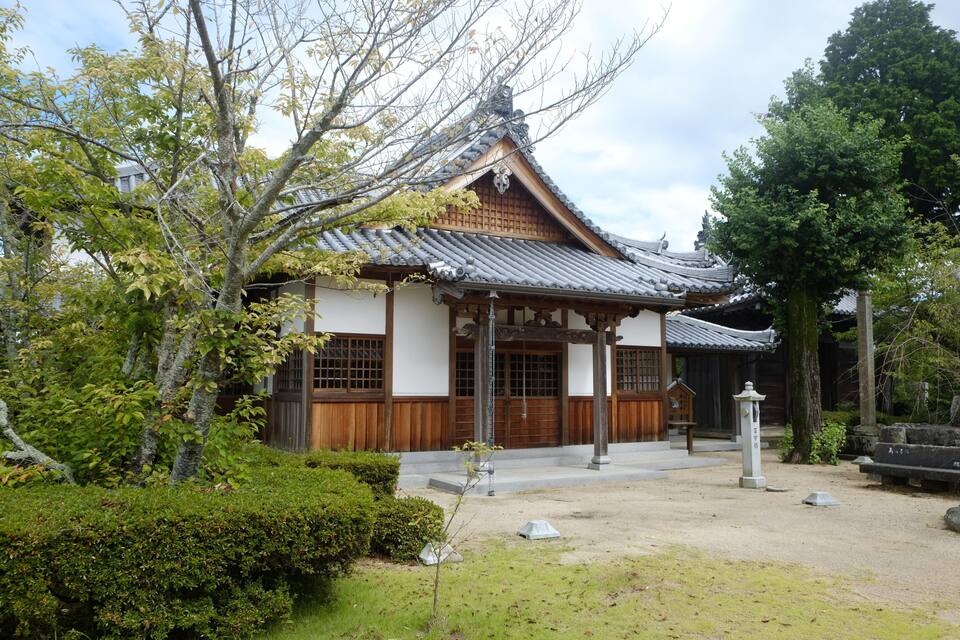 A traditional Japanese building with a tiled roof, wooden beams, and a stone lantern.