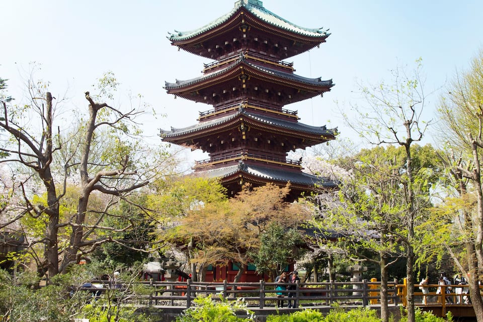 A traditional multi-tiered pagoda surrounded by a serene pond and lush greenery.
