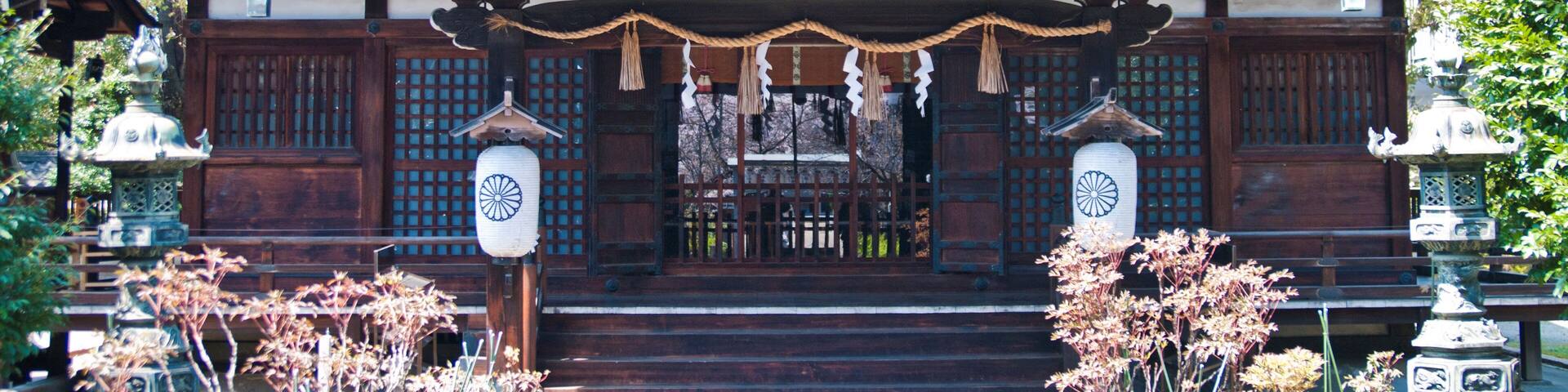 A traditional Japanese building with a tiled roof, wooden doors, and a stone lantern.