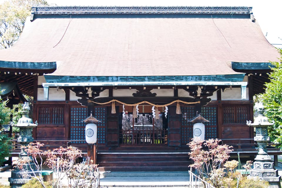 A traditional Japanese building with a tiled roof, wooden doors, and a stone lantern.