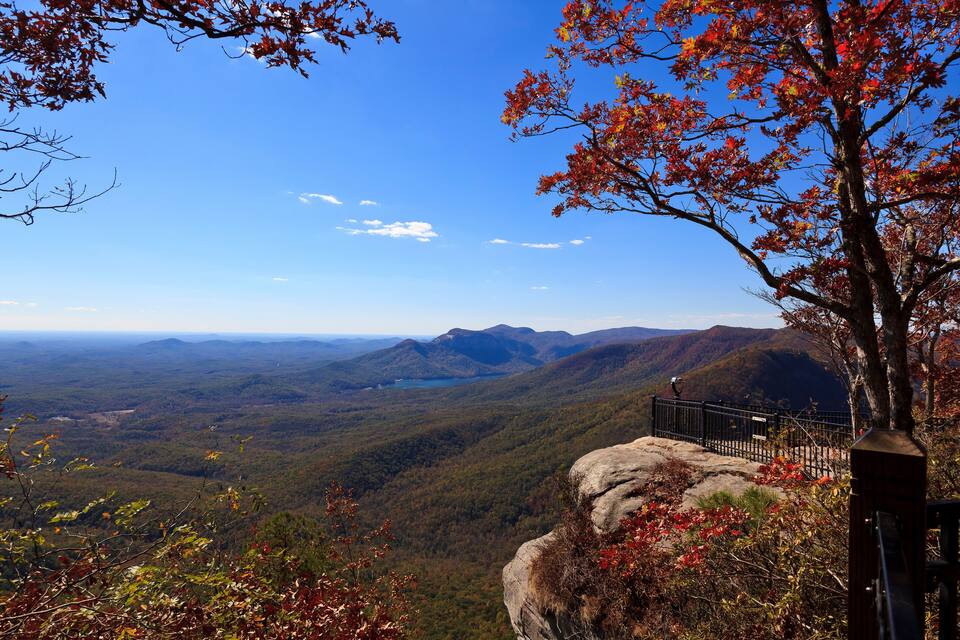 A mountainous landscape with autumn foliage, a clear sky, and a distant lake.