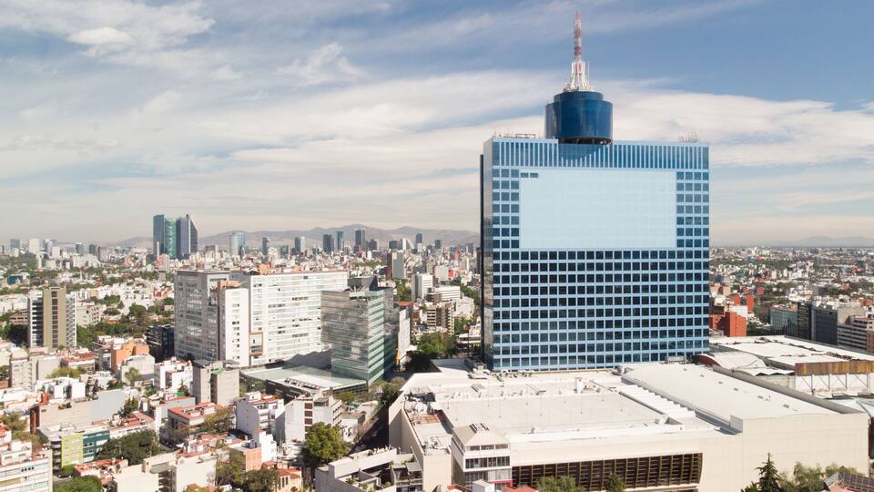A cityscape with a prominent blue skyscraper and surrounding buildings.