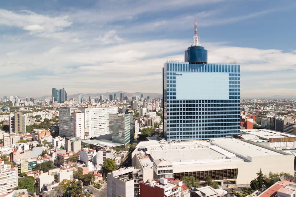 Un paisaje urbano con un rascacielos azul destacado y edificios circundantes.