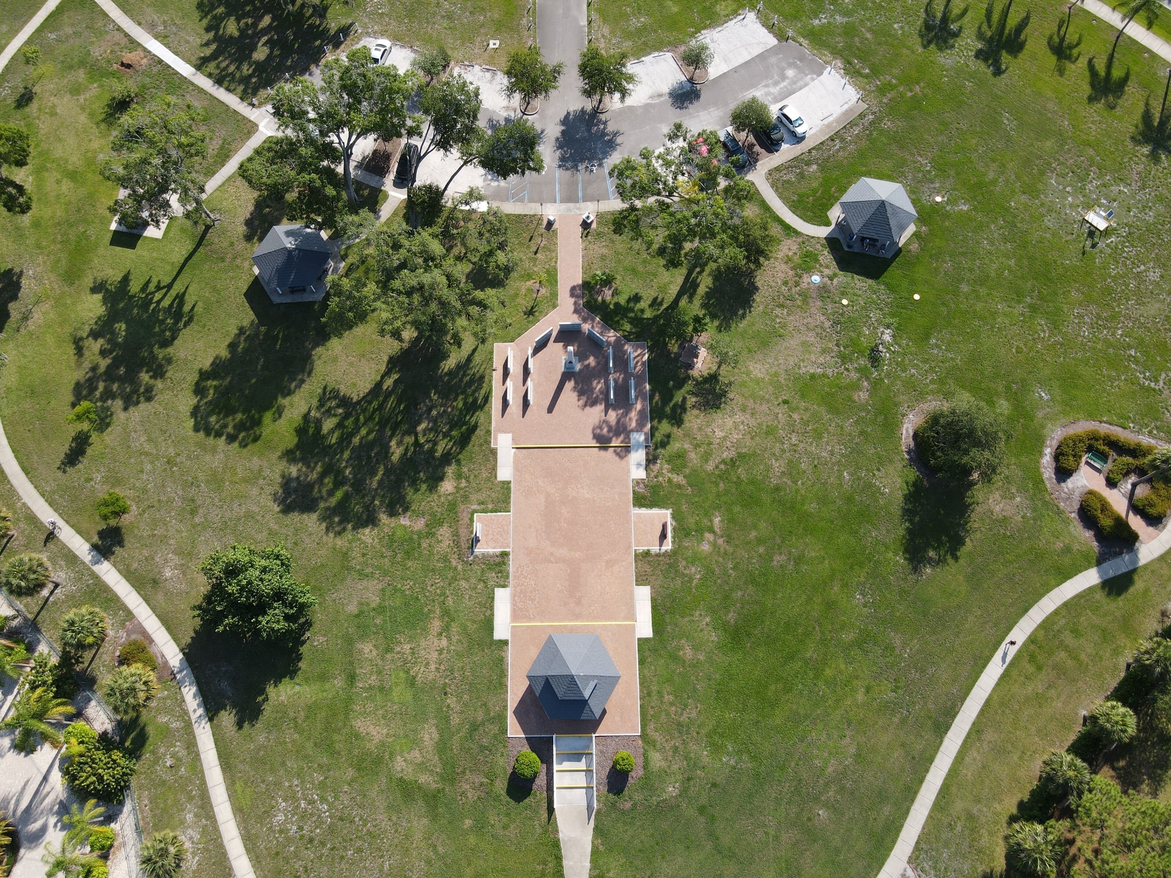 Drone photography of Veterans Memorial Park in Oldsmar, Florida, a waterside park featuring a memorial, a bocce court, fitness equipment, trails, and a gazebo in Tampa Bay