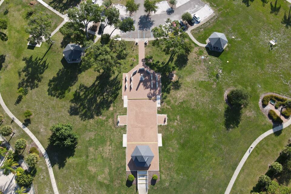 An aerial view of a park with a central building, pathways, and surrounding greenery.