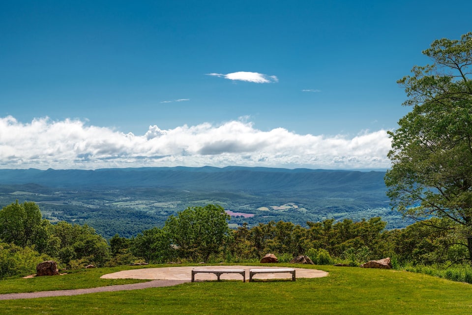 A park with a bench overlooking a valley and mountains.