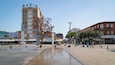A plaza with a fountain, a MAXIM building, and various shops.