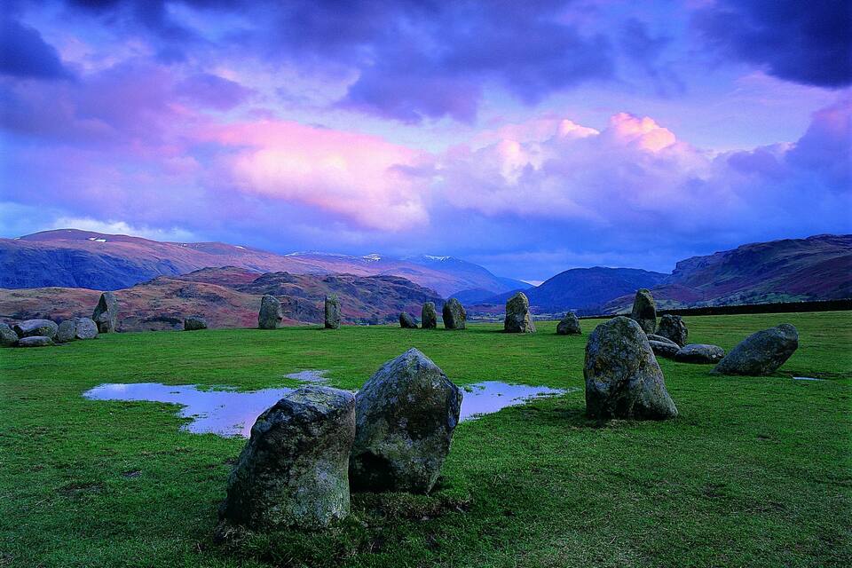 A stone circle in a grassy field with a dramatic sky.