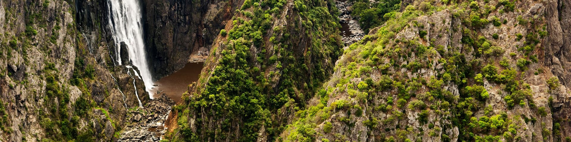 A waterfall cascading down a steep cliff surrounded by dense greenery.