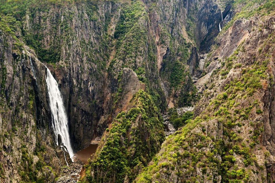 Ein Wasserfall stürzt über eine steile Klippe, umgeben von dichtem Grün.