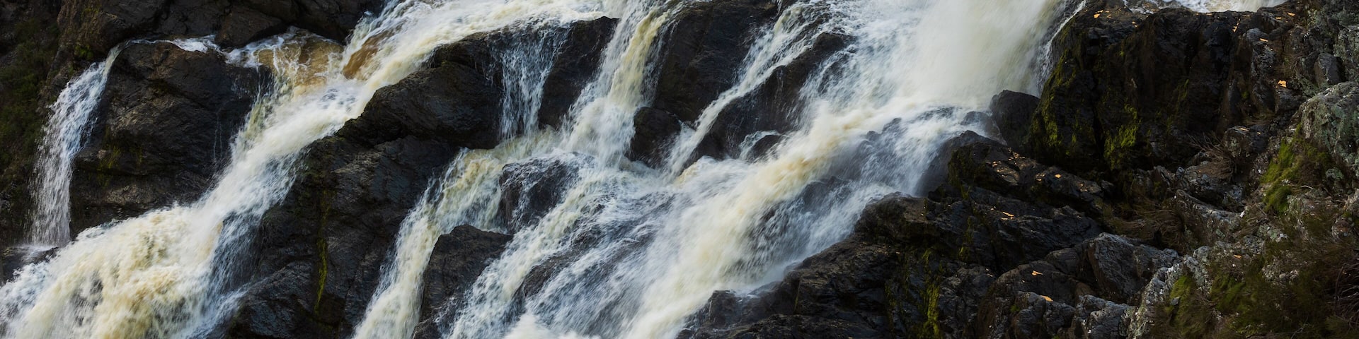 Una cascada imponente que se precipita sobre rocas oscuras y escarpadas.