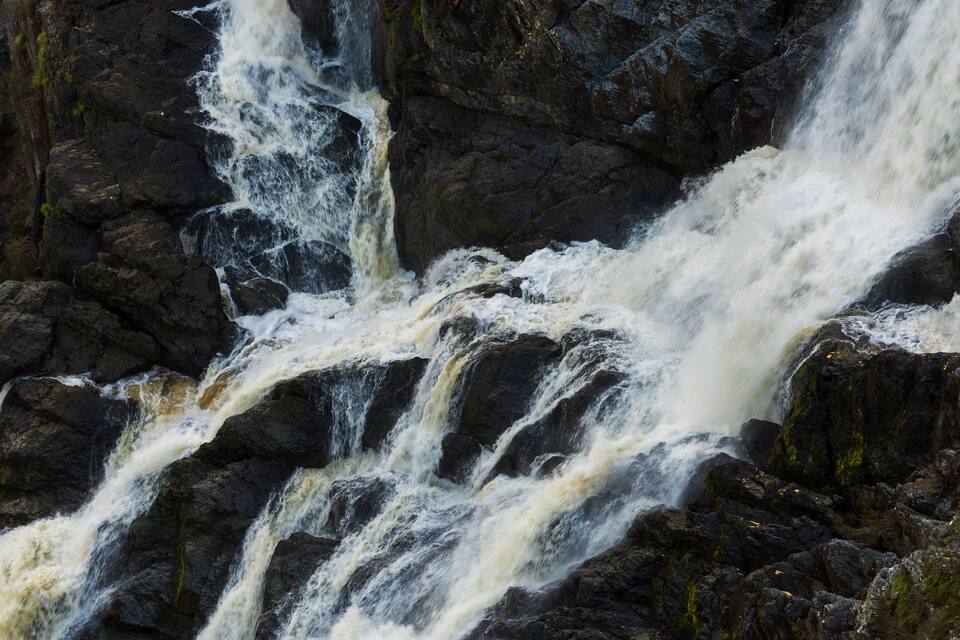 Uma cachoeira imponente despencando sobre rochas escuras e acidentadas.