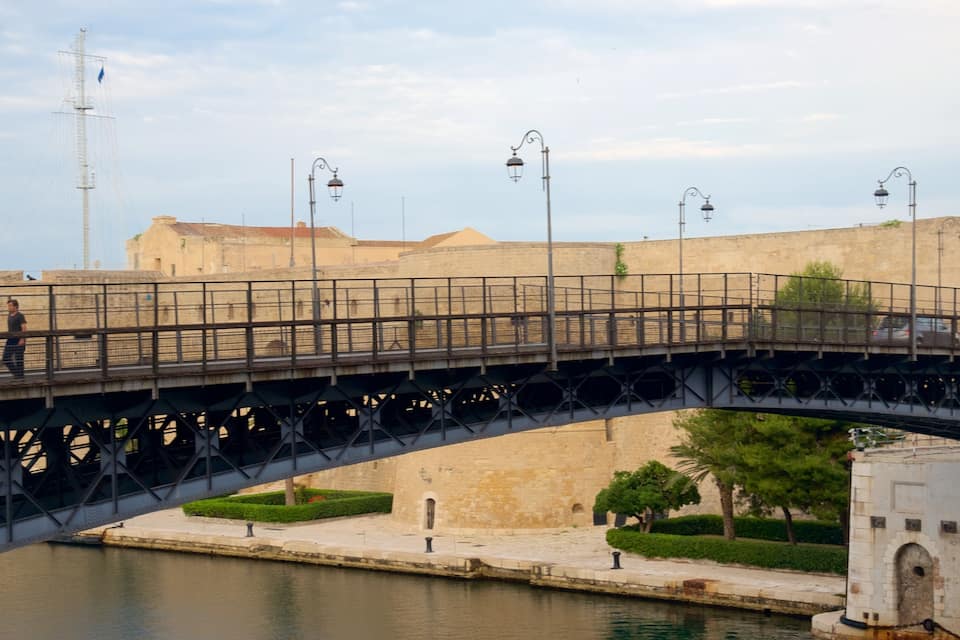 A bridge over a river with a historic building in the background.