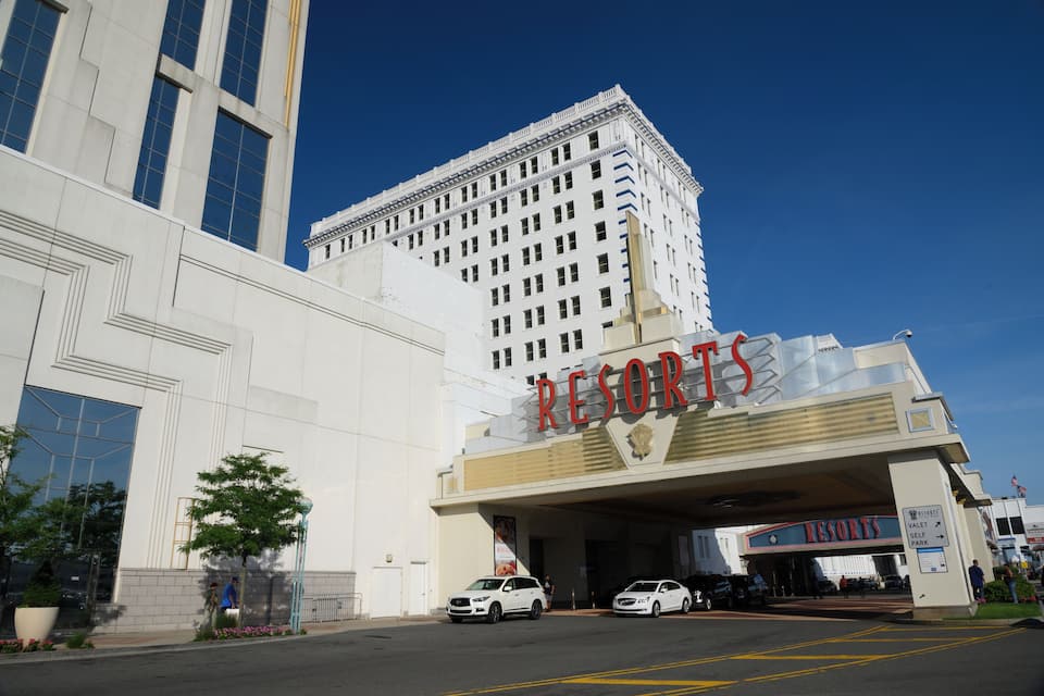 Un edificio grande con un letrero que dice "RESORTS" y un letrero más pequeño debajo. Hay coches estacionados frente al edificio.