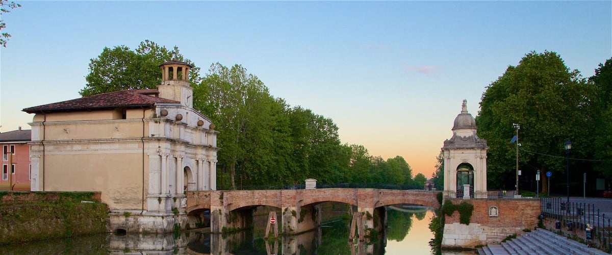 Puerta Ognissanti mostrando un puente, un río o arroyo y un atardecer