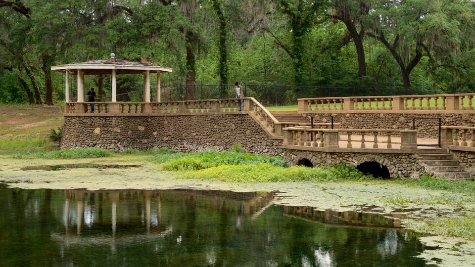 A stone bridge with a gazebo, a pond, and trees in the background.