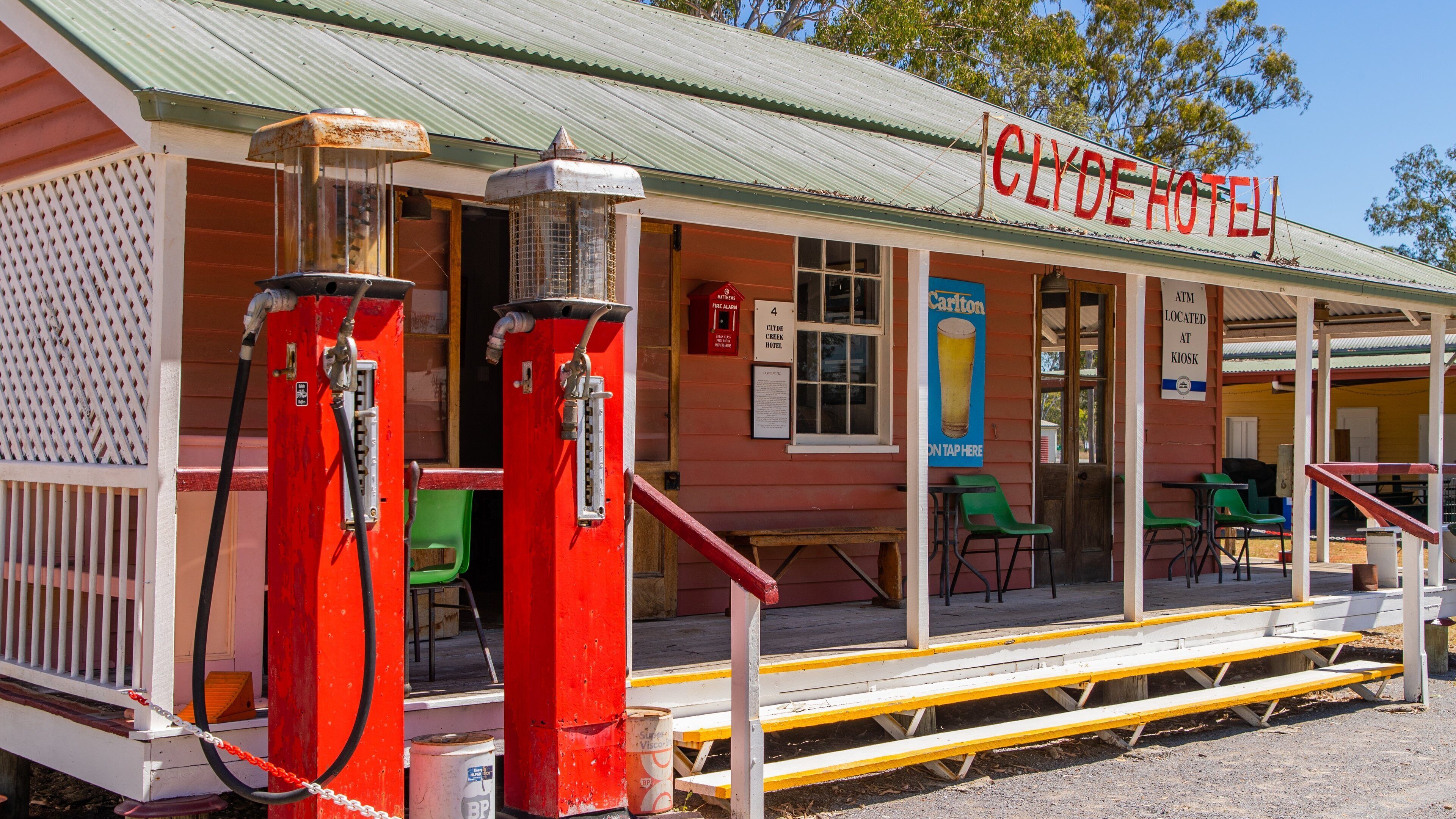 A red Clyde Hotel with outdoor seating and two gas pumps.