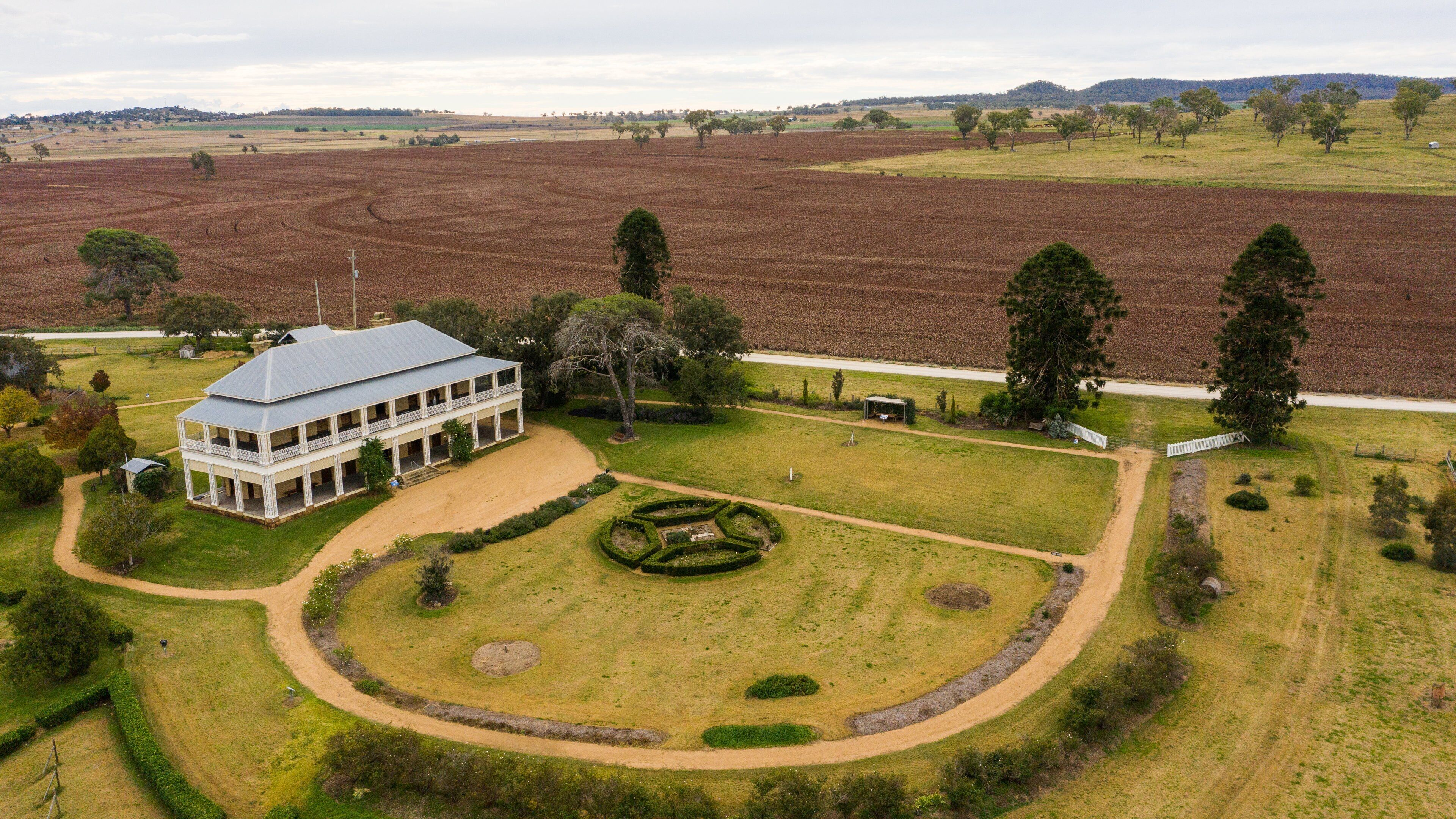 A large estate with a white building, a circular garden, and expansive fields.