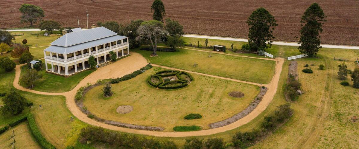 A large estate with a white building, a circular garden, and expansive fields.