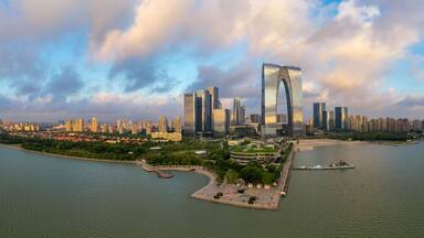 A river with a cityscape on the opposite bank, featuring modern skyscrapers and a distinctive curved building.