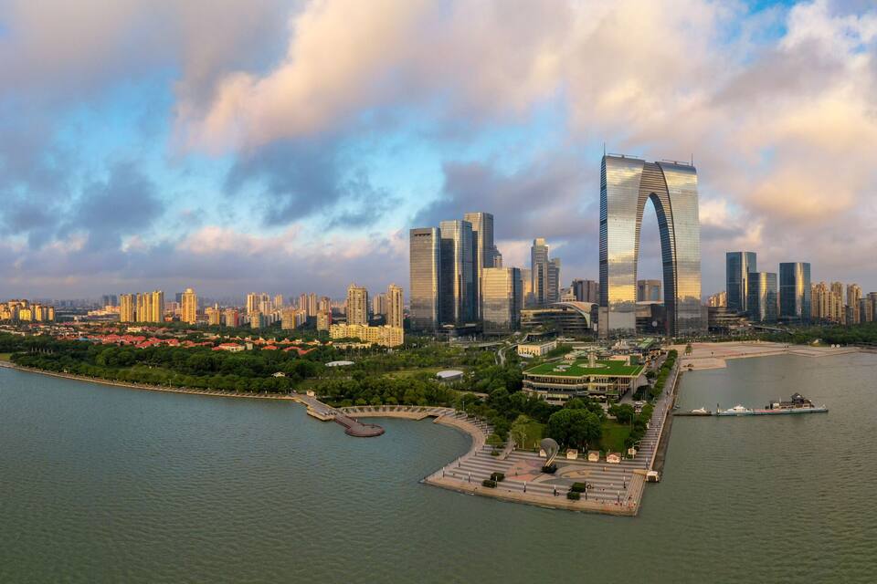 Een rivier met een stadsgezicht aan de overkant, met moderne wolkenkrabbers en een opvallend gebogen gebouw.