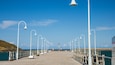 A wooden pier with white lamp posts extending over the water.