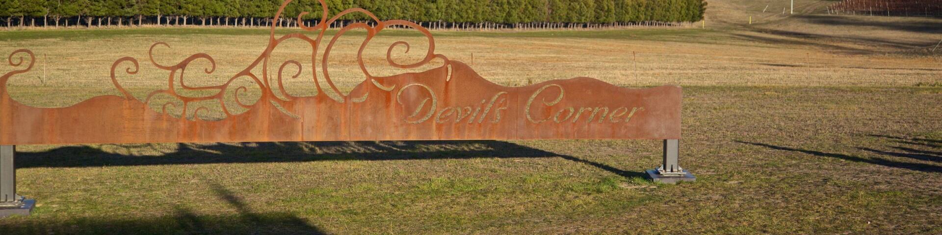 A scenic landscape with a large metal sign reading "David's Corner," a grassy field, a forested area, and distant mountains.