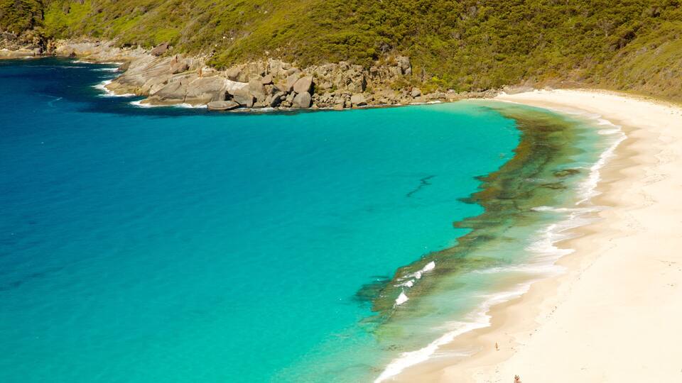 A turquoise beach with clear waters, sandy shore, and rocky coastline.