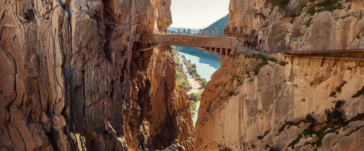 A wooden bridge over a canyon with a river below.